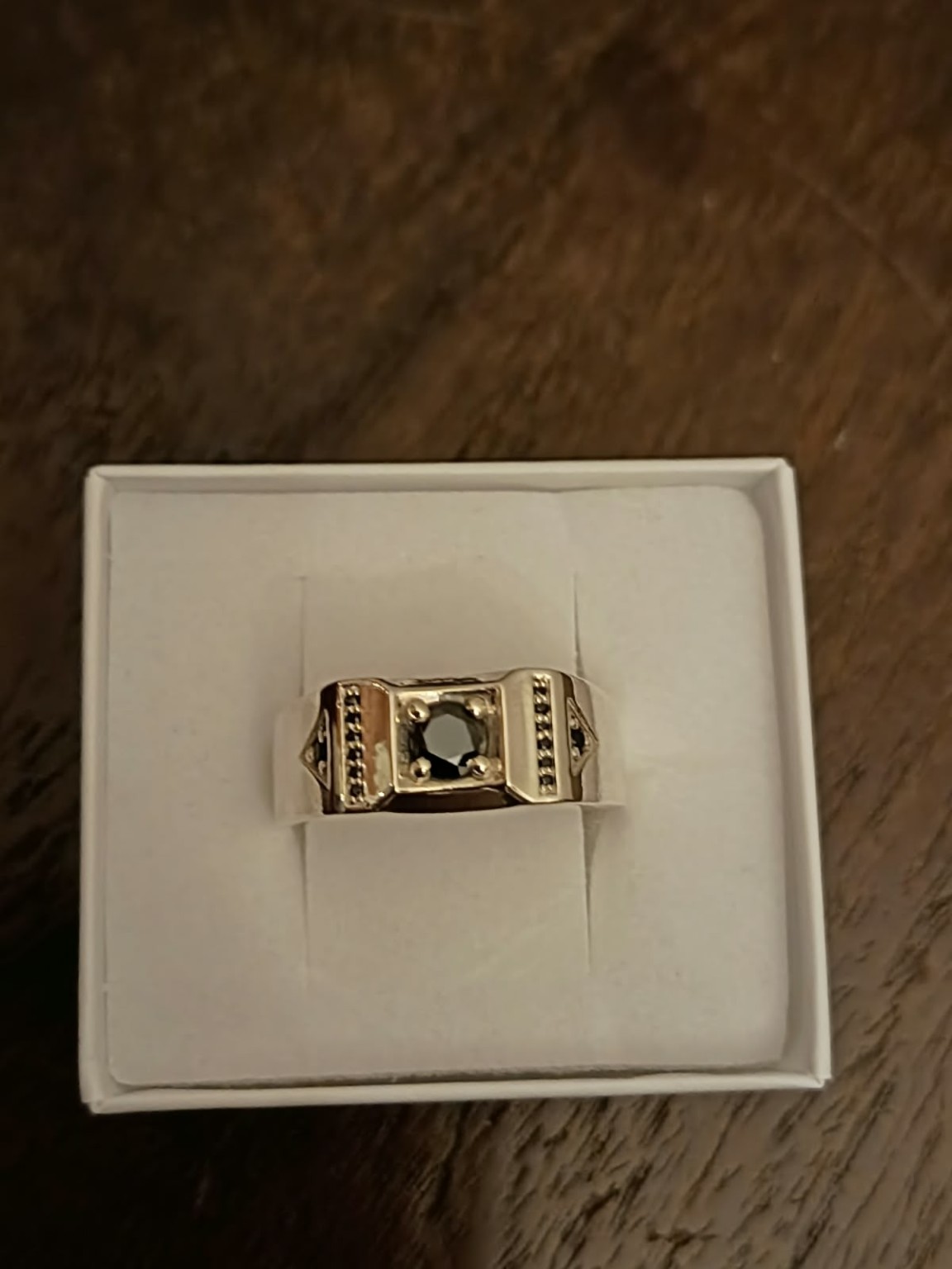 Anillo de sello con piedra central oscura y detalles laterales