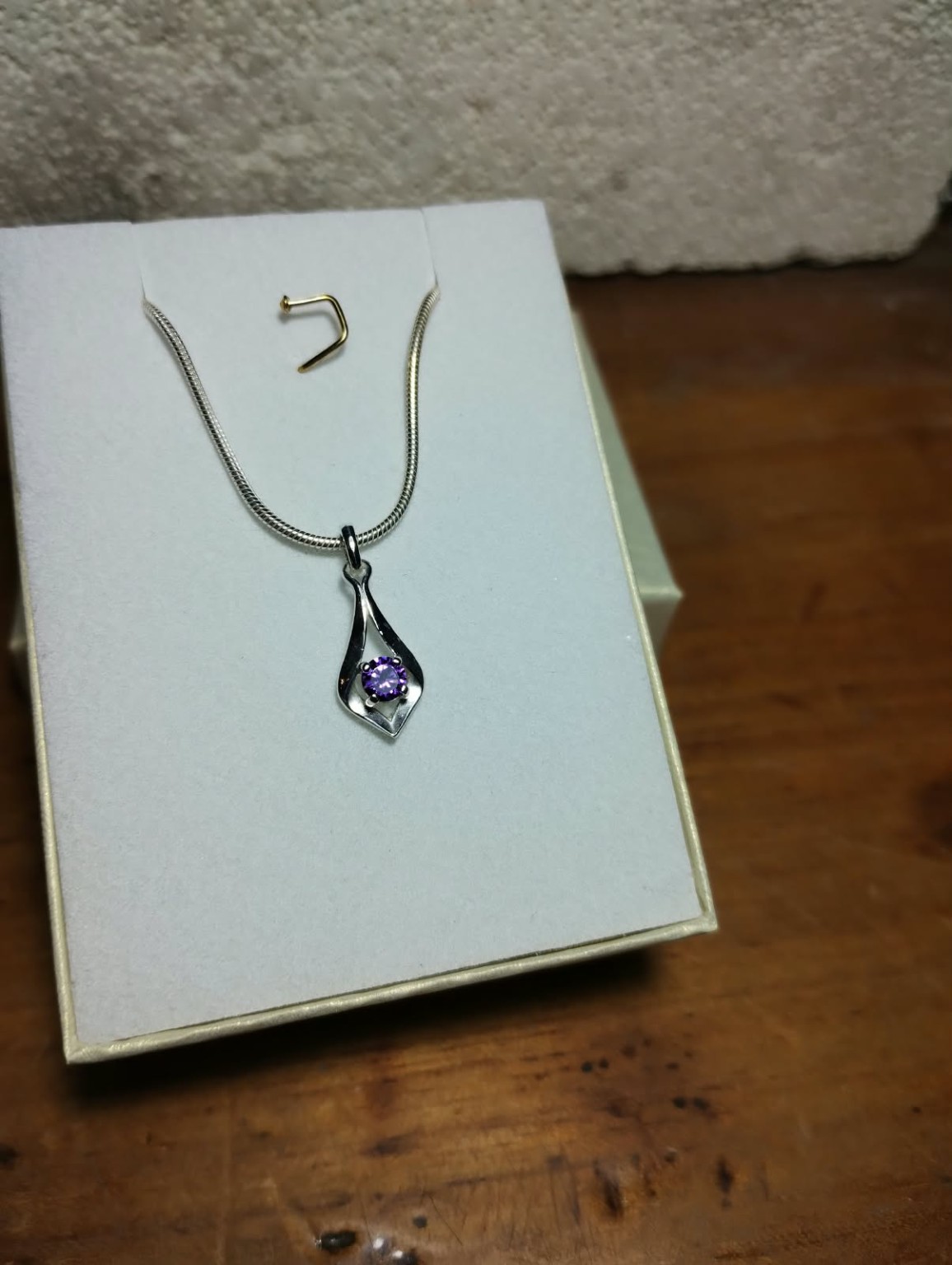 Dije de líneas curvas con una piedra violeta